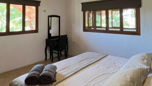 Een slaapkamer met een bed, een bureau, een stoel en een plafondventilator.