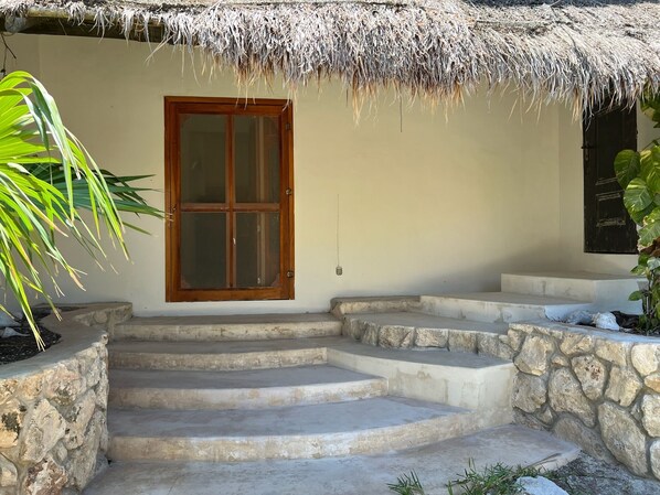 Un edificio con tejado de paja, puerta de madera y escalones de piedra que llevan a la entrada.