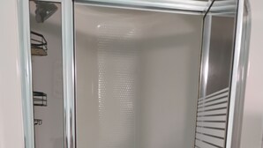 A modern, enclosed shower area with a glass door and a metal frame.