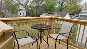 A wooden deck with a glass table and two chairs.