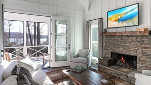 A cozy living room with a fireplace, a comfortable sofa, and a television mounted above it.