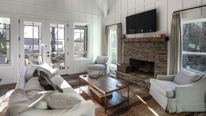 A spacious living room with a fireplace, white furniture, and large windows.
