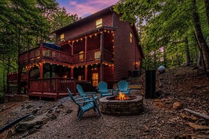 Une cabane dotée d’une terrasse, de meubles de jardin et d’un foyer extérieur.