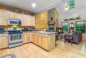 Une cuisine dotée de meubles en bois, d’un four à micro-ondes, d’un four traditionnel et d’un coin repas comprenant un canapé et une table.