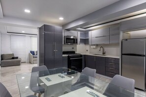 Una cocina moderna con una mesa de comedor de vidrio, electrodomésticos de acero inoxidable y armarios grises.