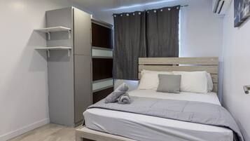 A bedroom with a bed, a wardrobe, and an air conditioning unit.