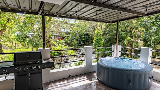 An outdoor patio with a grill and a hot tub. - Sabana River Villa Las Paylas (Bo Sabana Sec The Widows)