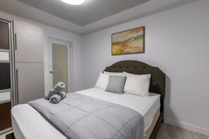 Un dormitorio con cama, una puerta y un cuadro en la pared.