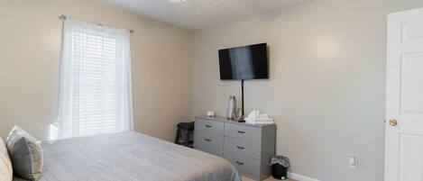A bedroom with a bed, a dresser, a television, and a ceiling fan.