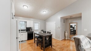 A kitchen with white cabinets, a dark wooden island, and a dining area with a table and chairs. - Spacious 3bd/2ba near Casino (Danville)