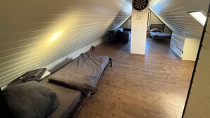 A compact attic bedroom with two beds, a dartboard, and a small table. - Lots of space & comfort - ideal for fitters or vacation guests! (Orbis)
