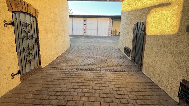 A covered outdoor area with brick flooring, a wooden ceiling, and a view of a building in the background. - Lots of space & comfort - ideal for fitters or vacation guests! (Orbis)