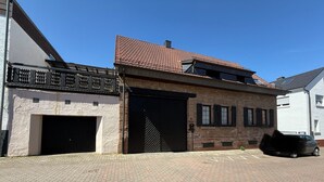 A building with a tiled roof, a garage door, and a paved driveway. - Lots of space & comfort - ideal for fitters or vacation guests! (Orbis)