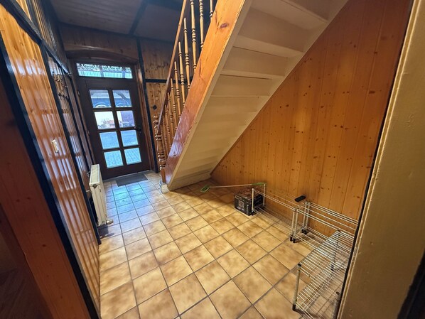 A wooden interior with a tiled floor, a staircase, and a door leading outside.