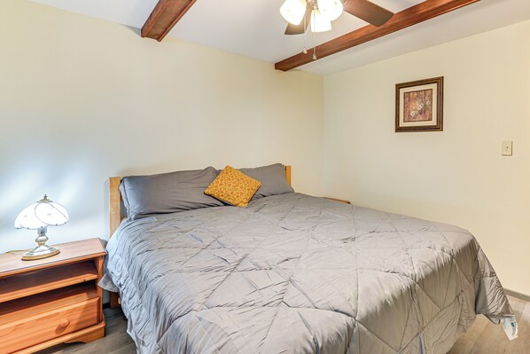 A bedroom with a bed, a nightstand, a lamp, and a framed picture on the wall. - Lake-View Cabin w/ Furnished Deck in Hadley! (Hadley)