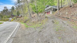 Ein Feldweg schlängelt sich durch einen bewaldeten Bereich, mit einem Haus auf einem Hügel.