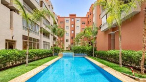 A swimming pool surrounded by greenery and multi-story buildings. - Luxury Apartment in Central Marrakech - Pool & Fast Wi-Fi (Marrakesh)