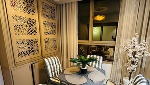 A dining area with a round table, striped chairs, a potted plant, and a decorative ceiling light. - Luxury Apartment in Central Marrakech - Pool & Fast Wi-Fi (Marrakesh)