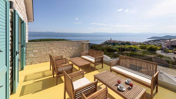 Un balcon doté de mobilier en bois et offrant une vue sur une ville côtière.