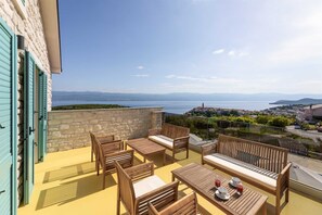 Un balcon doté de mobilier en bois et offrant une vue sur une ville côtière.