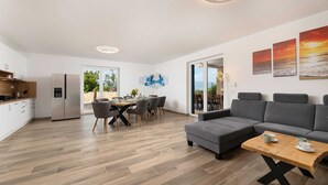 A modern living space with a kitchen, dining area, and a seating area with a sofa and coffee table. - Villa Maja– Stylish Oasis with Heated Pool & Sea View (Vrbnik (Krk))