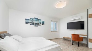 A modern bedroom with a bed, a desk, a chair, a TV, and artwork on the wall. - Villa Maja– Stylish Oasis with Heated Pool & Sea View (Vrbnik (Krk))
