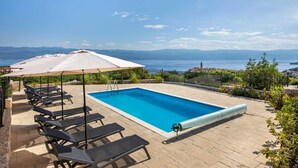 A swimming pool with lounge chairs and umbrellas, surrounded by greenery and a view of the sea and mountains. - Villa Maja– Stylish Oasis with Heated Pool & Sea View (Vrbnik (Krk))