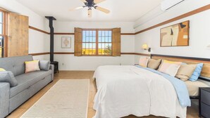 Een slaapkamer met een bed, een bank, een raam met uitzicht, een plafondventilator en een airconditioner.