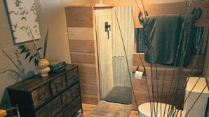 A bathroom with wooden flooring, a white toilet, a dark wooden cabinet, and a shower area. - Tent Cholla, occupancy near Saguaro NP (Marana)
