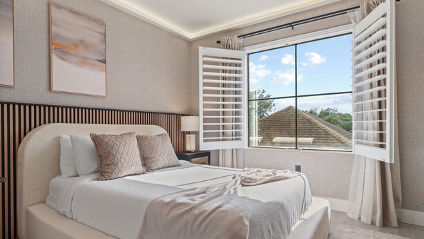 Un dormitorio con una cama grande, una ventana con persianas, una mesita de noche y una obra de arte colgada en la pared.