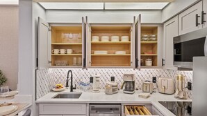 Una cocina moderna con armarios abiertos, lavavajillas y microondas.