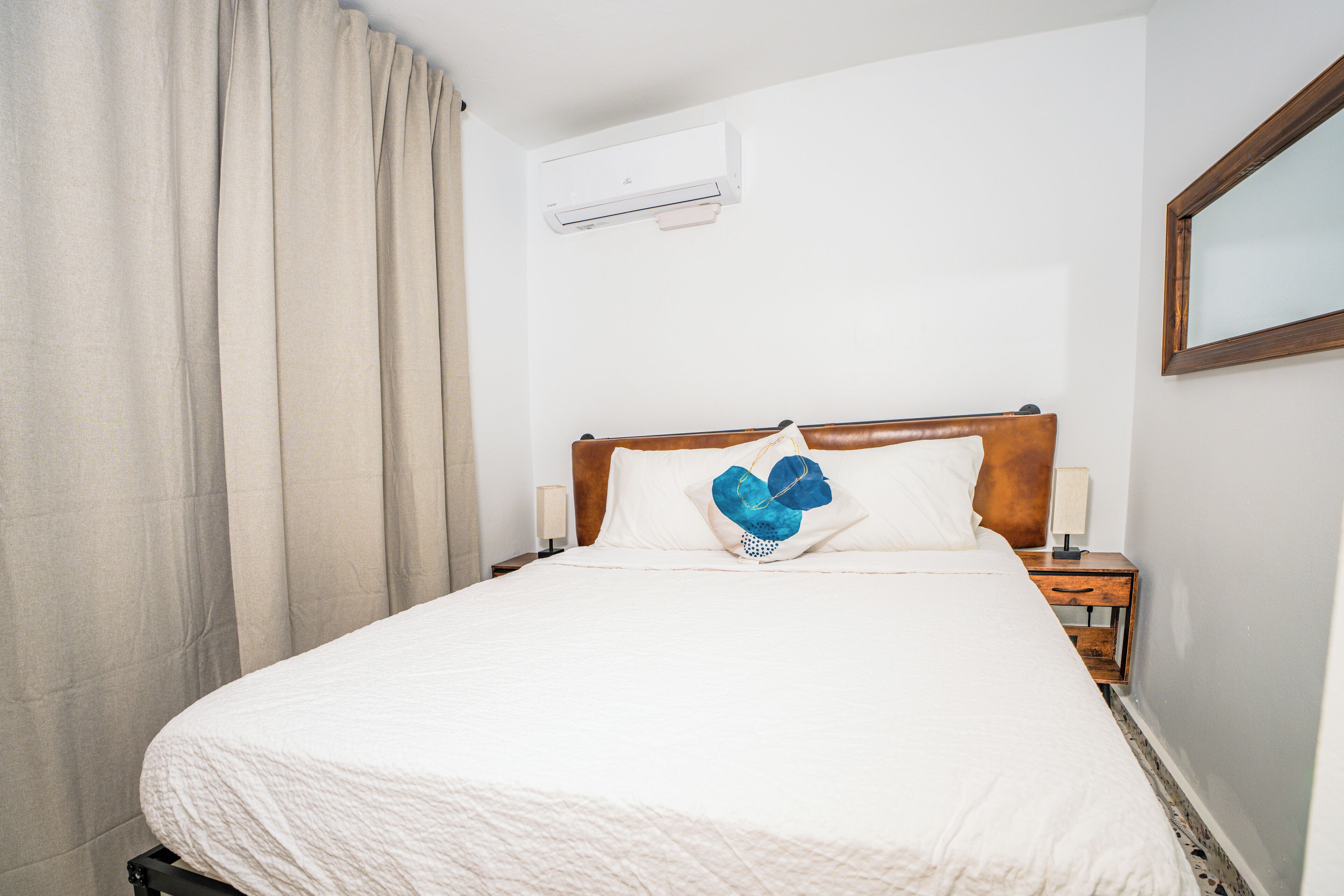 Una cama bien hecha con una colcha blanca y una almohada azul en forma de corazón.