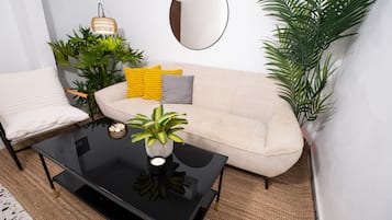 Una sala de estar con un sofá, una mesa de centro, un espejo y varias plantas.