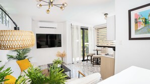A modern living room with a TV, sofa, and dining area. - Garden of Eden Hotel (Vega Alta)