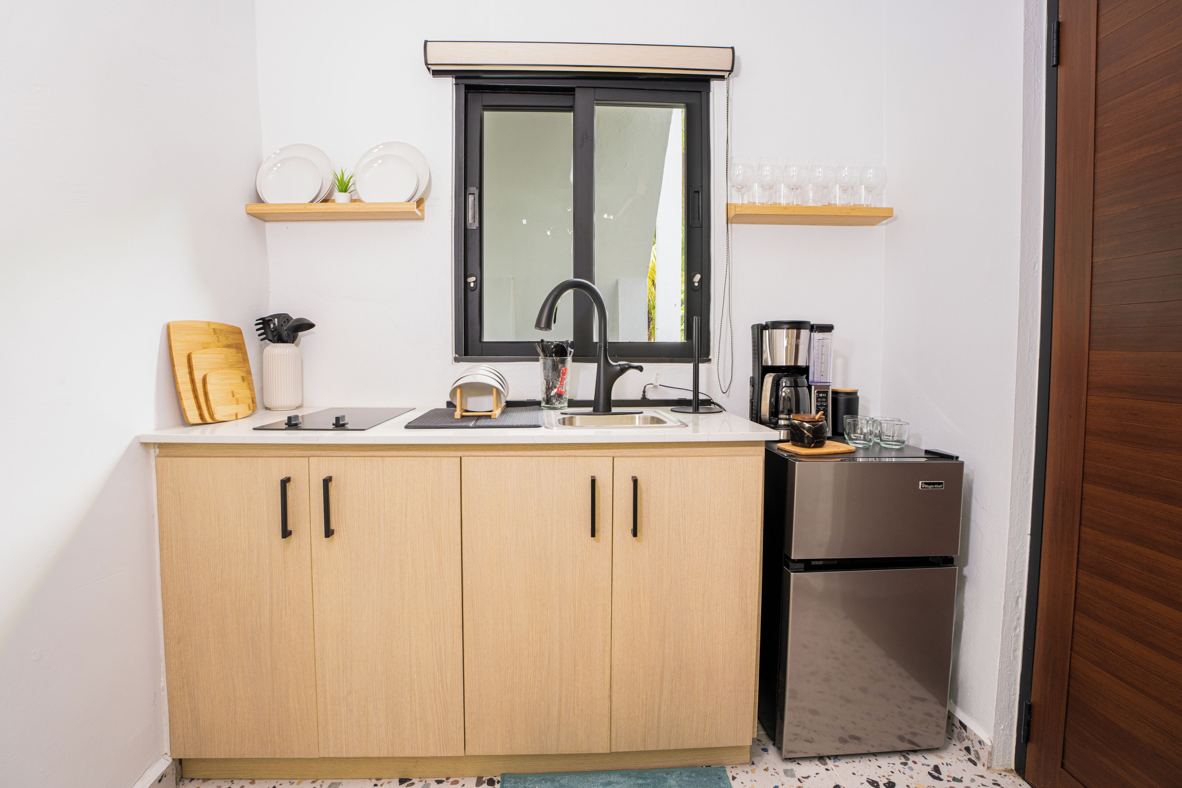 Una cocina compacta con un lavamanos, cafetera y refrigerador.