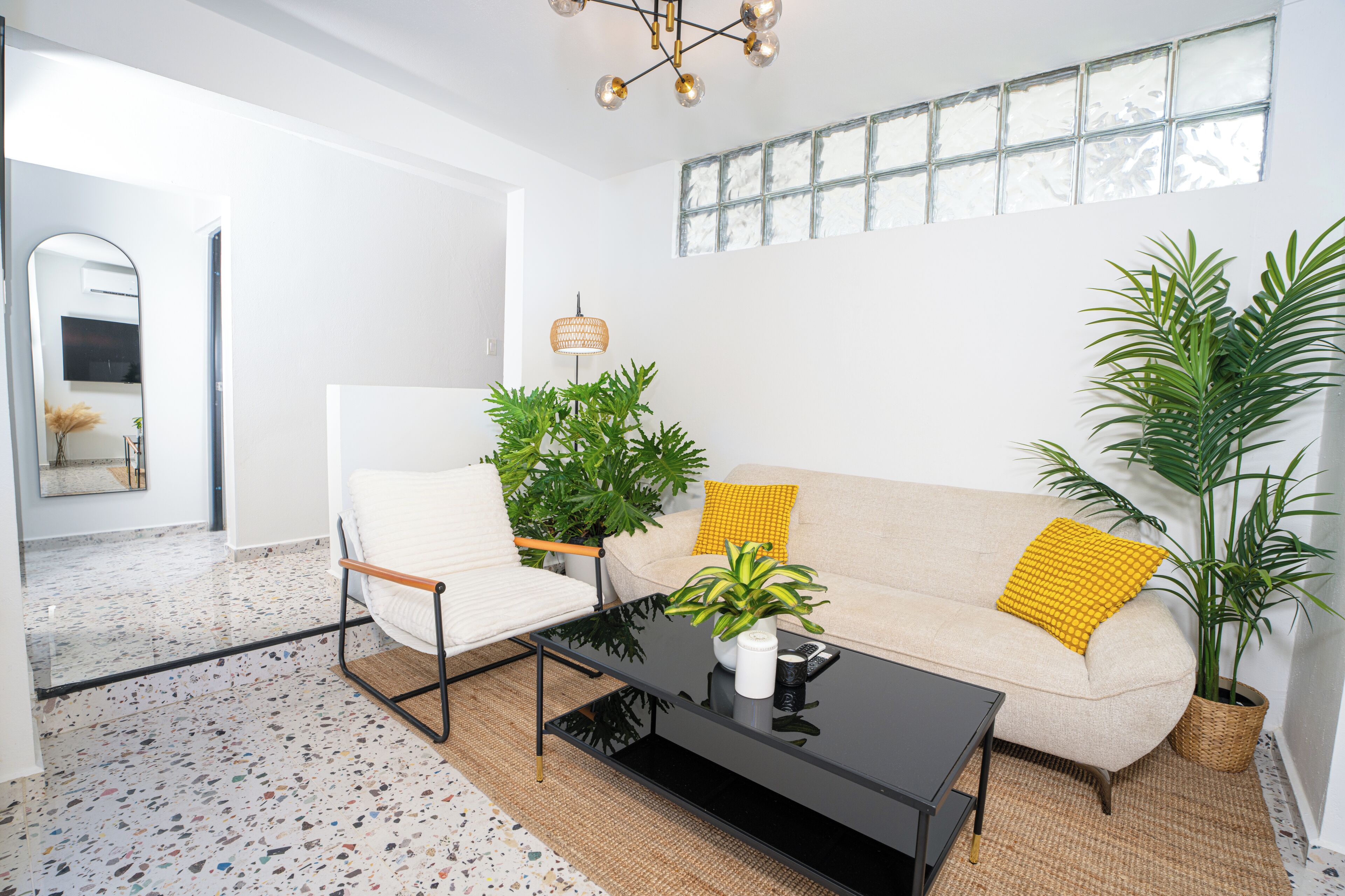 A modern living room with a sofa, armchairs, a coffee table, and potted plants.