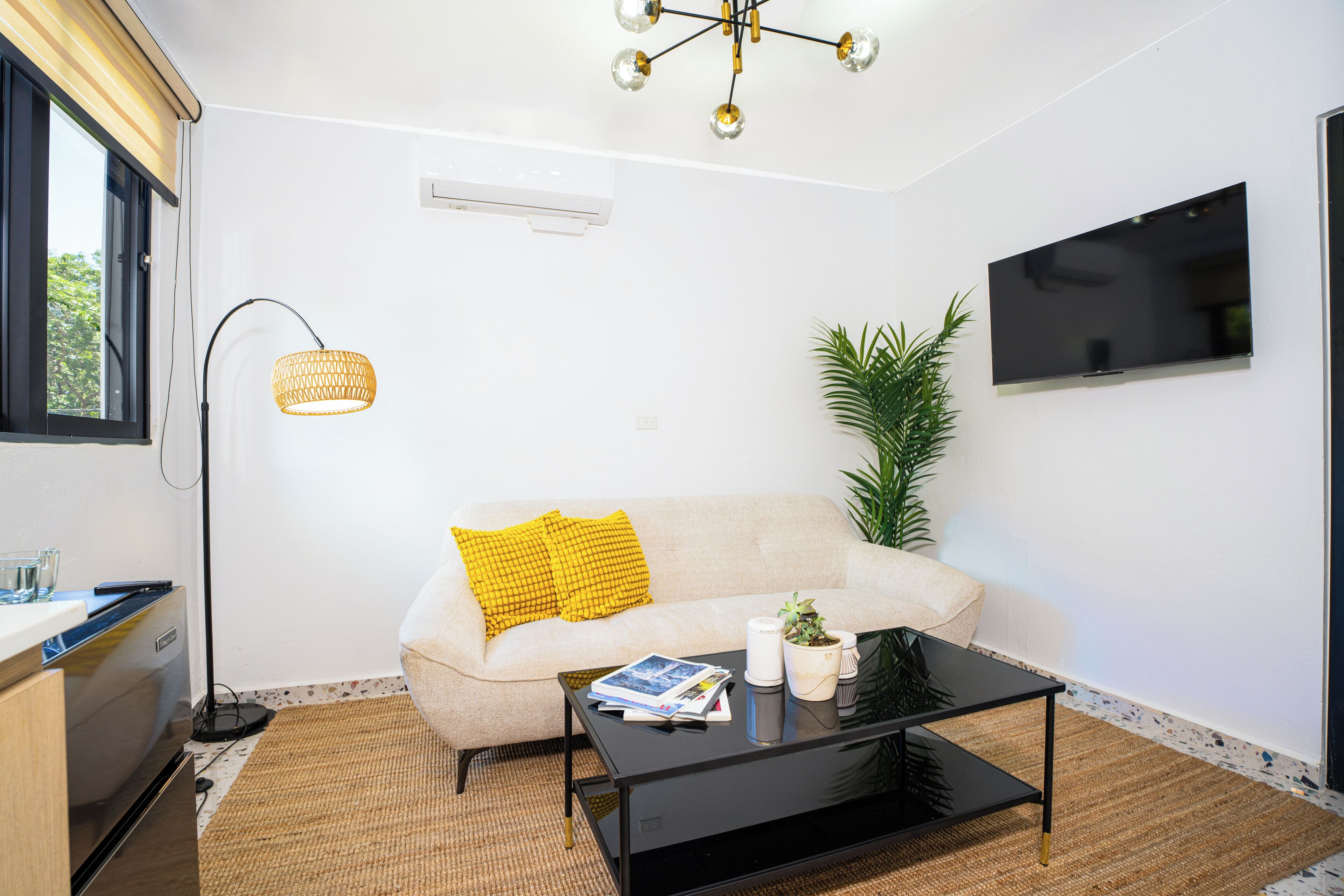 A modern living room with a sofa, coffee table, floor lamp, and a TV mounted on the wall.
