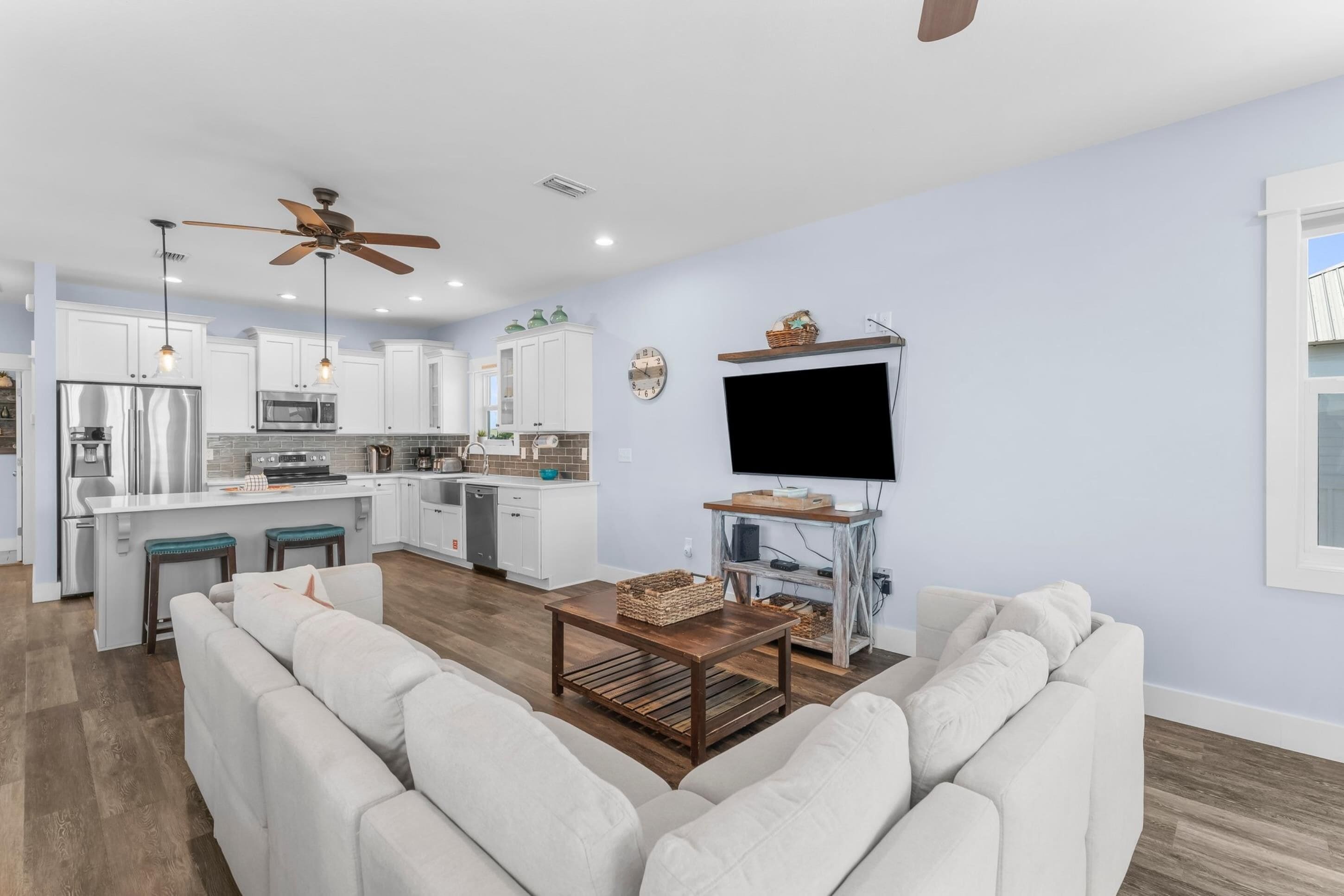A modern kitchen with white cabinets, a built-in microwave, and a large island.