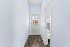 Un couloir étroit avec une porte bleu clair donnant sur un balcon.