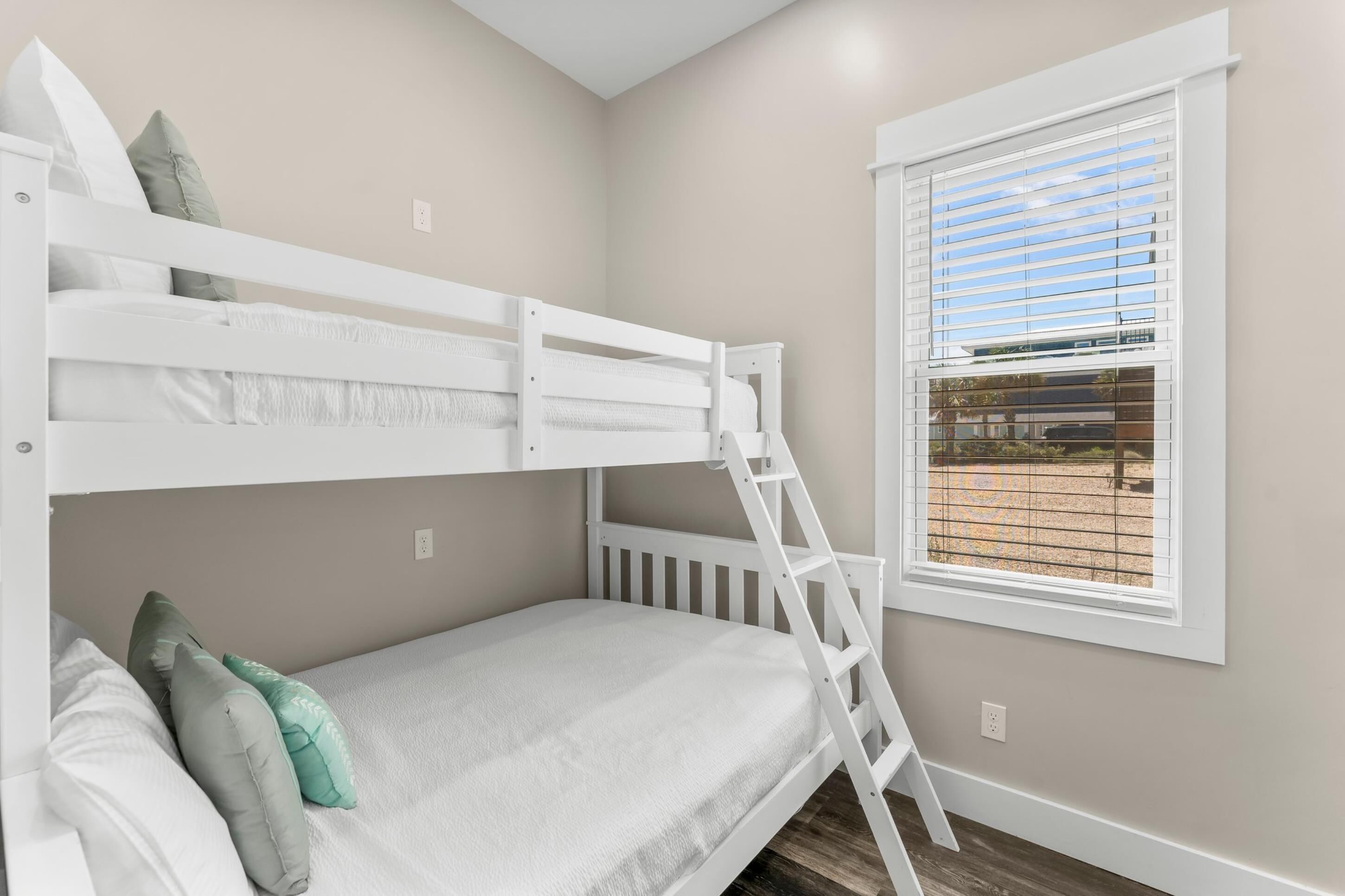 Quarto com beliche, escada, janela com persianas e vista para área externa.