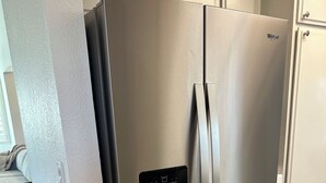 A stainless steel Whirlpool refrigerator with a water and ice dispenser, located in a kitchen with wooden flooring and white cabinetry. - 4BR/2.5BA House in Delightful Lancaster with WiFi, AC and Large Yard (Lancaster)