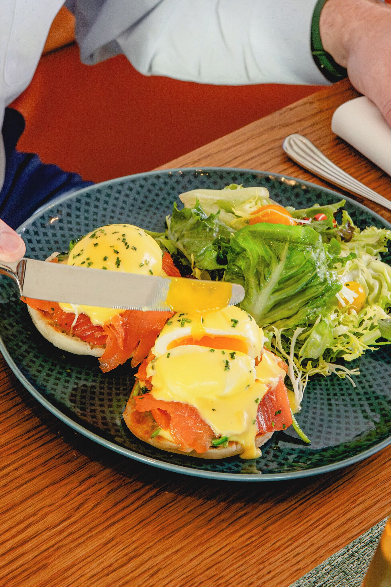 A plate with a sandwich, salad, and a knife.