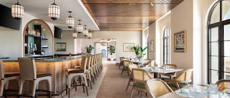 En restaurant med barområde, træloft og store vinduer.