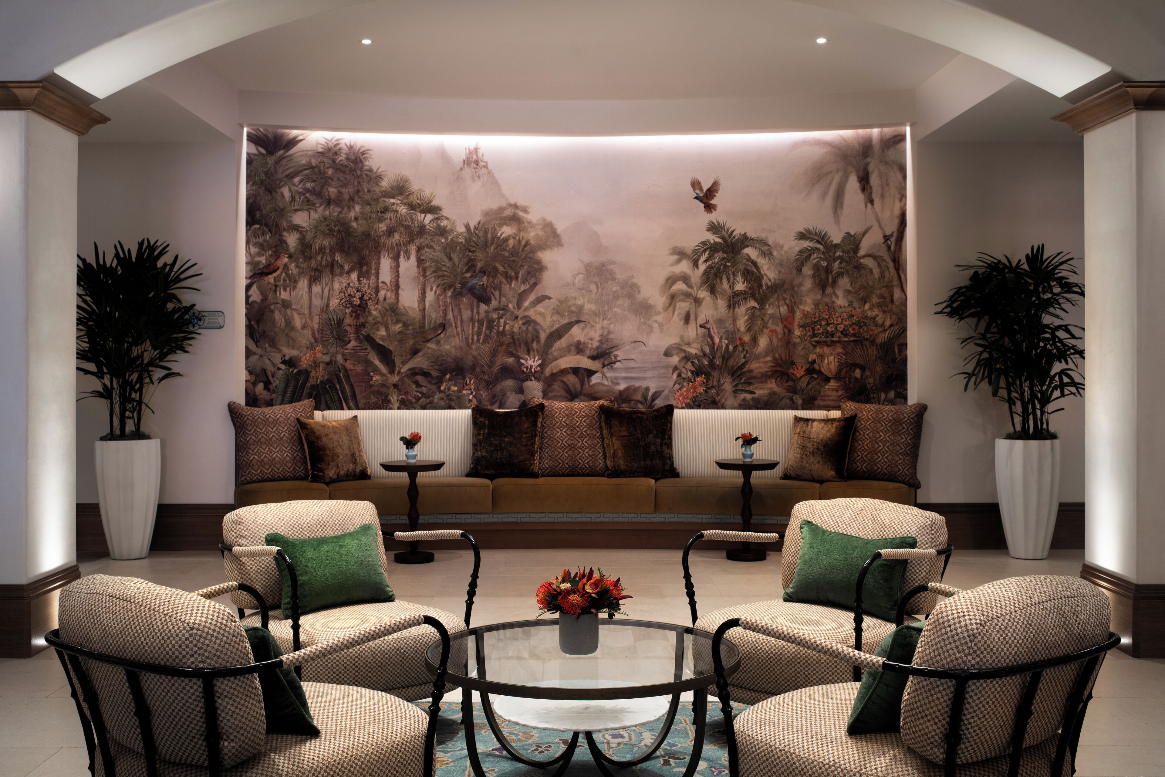 A living room with a large mural, two sofas, a coffee table, and four armchairs.