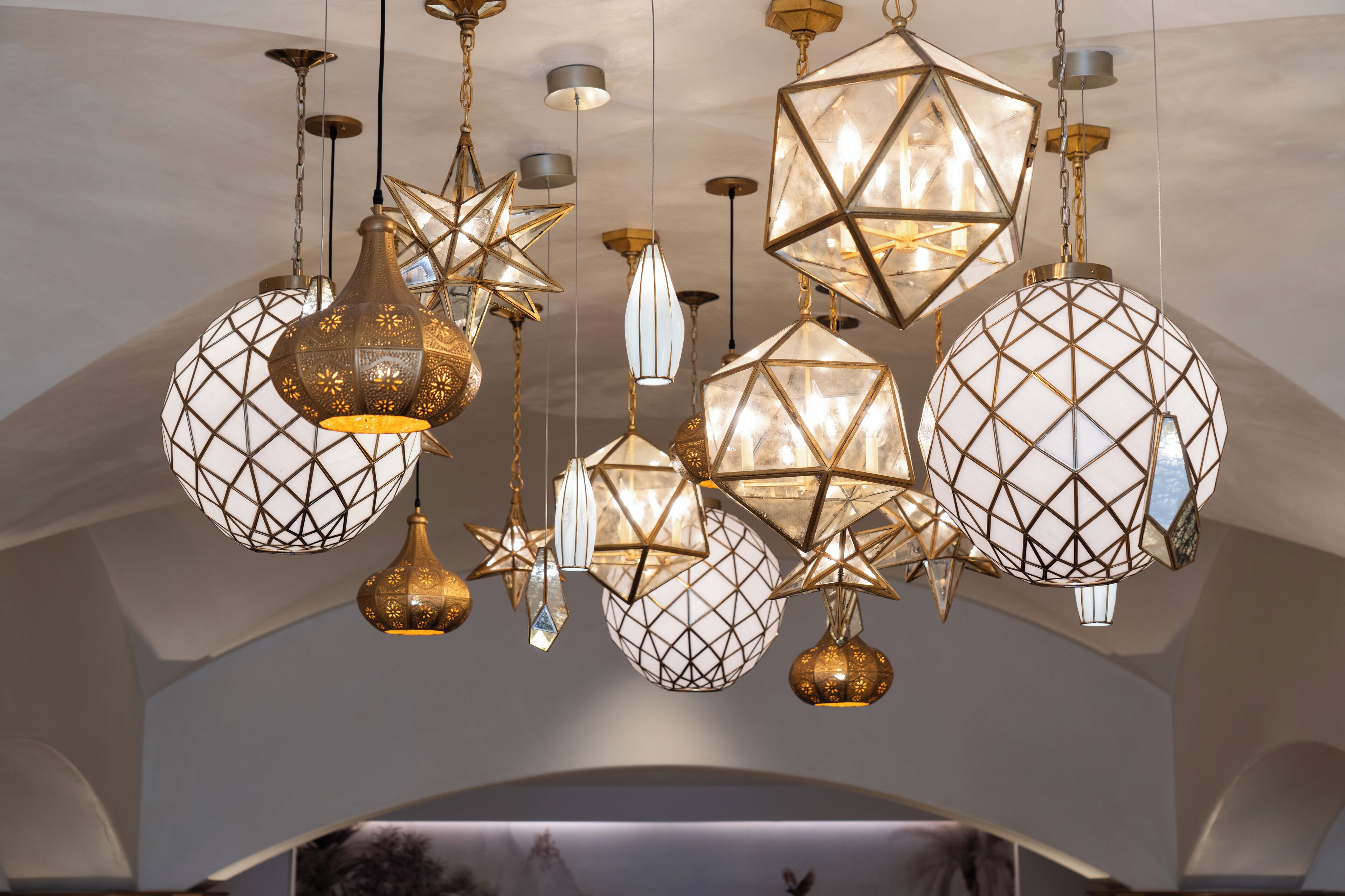 A chandelier with geometric and star-shaped light fixtures in a room with arched ceilings.