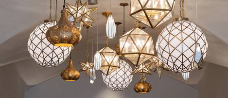 A chandelier with geometric and star-shaped light fixtures in a room with arched ceilings.