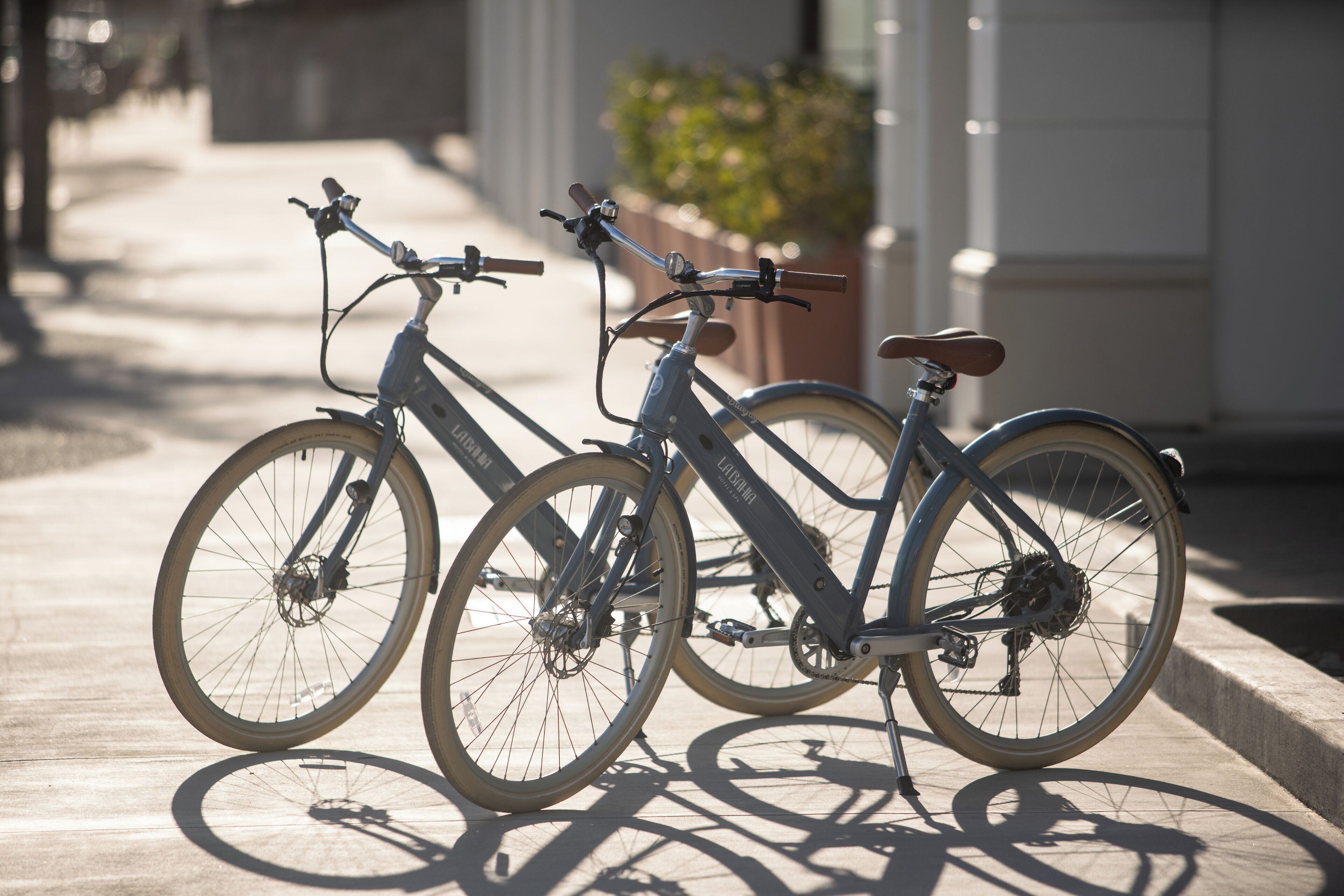 Two bicycles parked on a sidewalk next to a building.