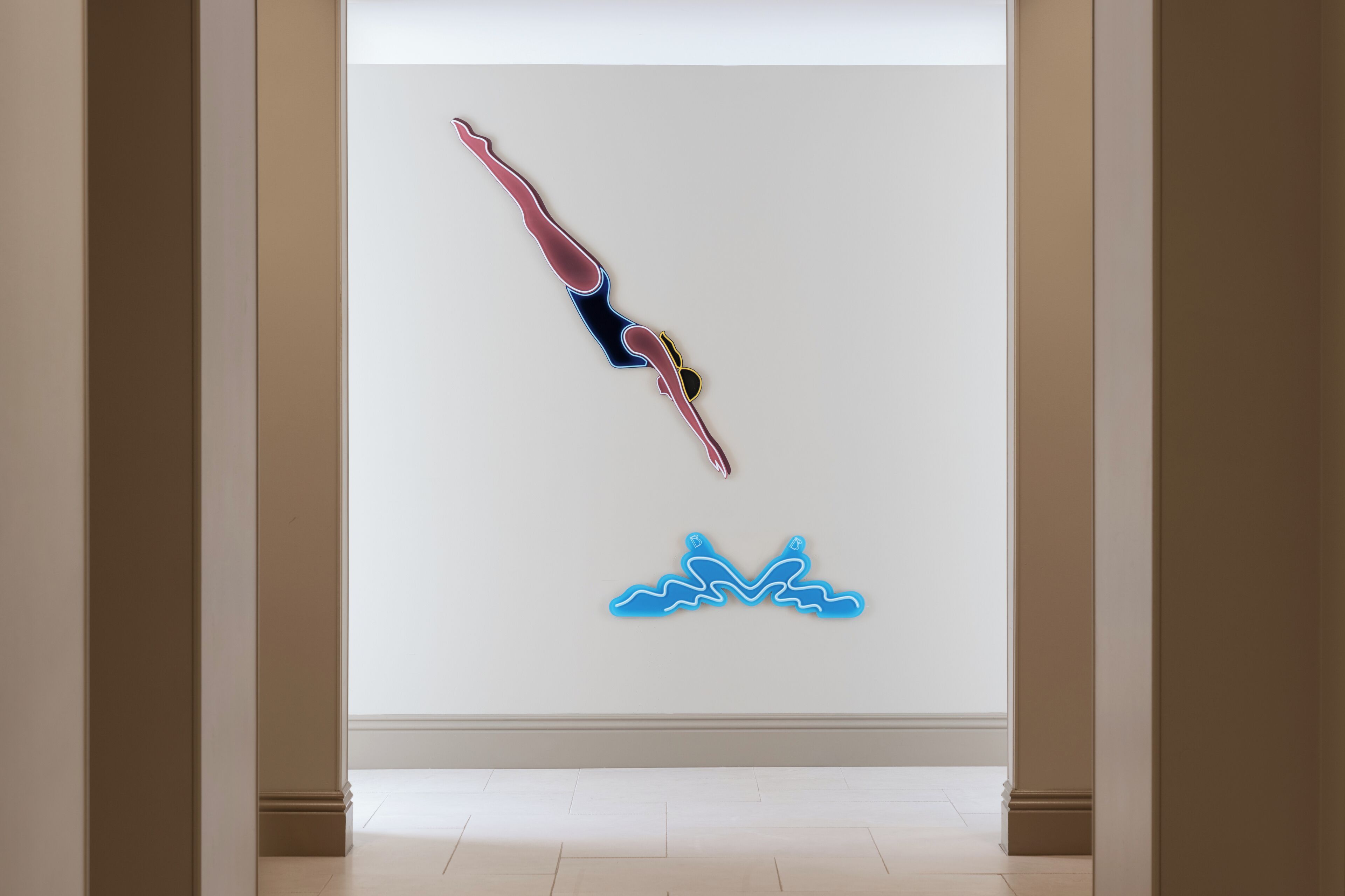 Een hal met een neonkunstwerk op de muur, waarop een duiker afgebeeld is.
