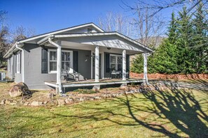 Een gelijkvloers huis met een overdekte veranda, een klein terras en een stenen rand rond de tuin.