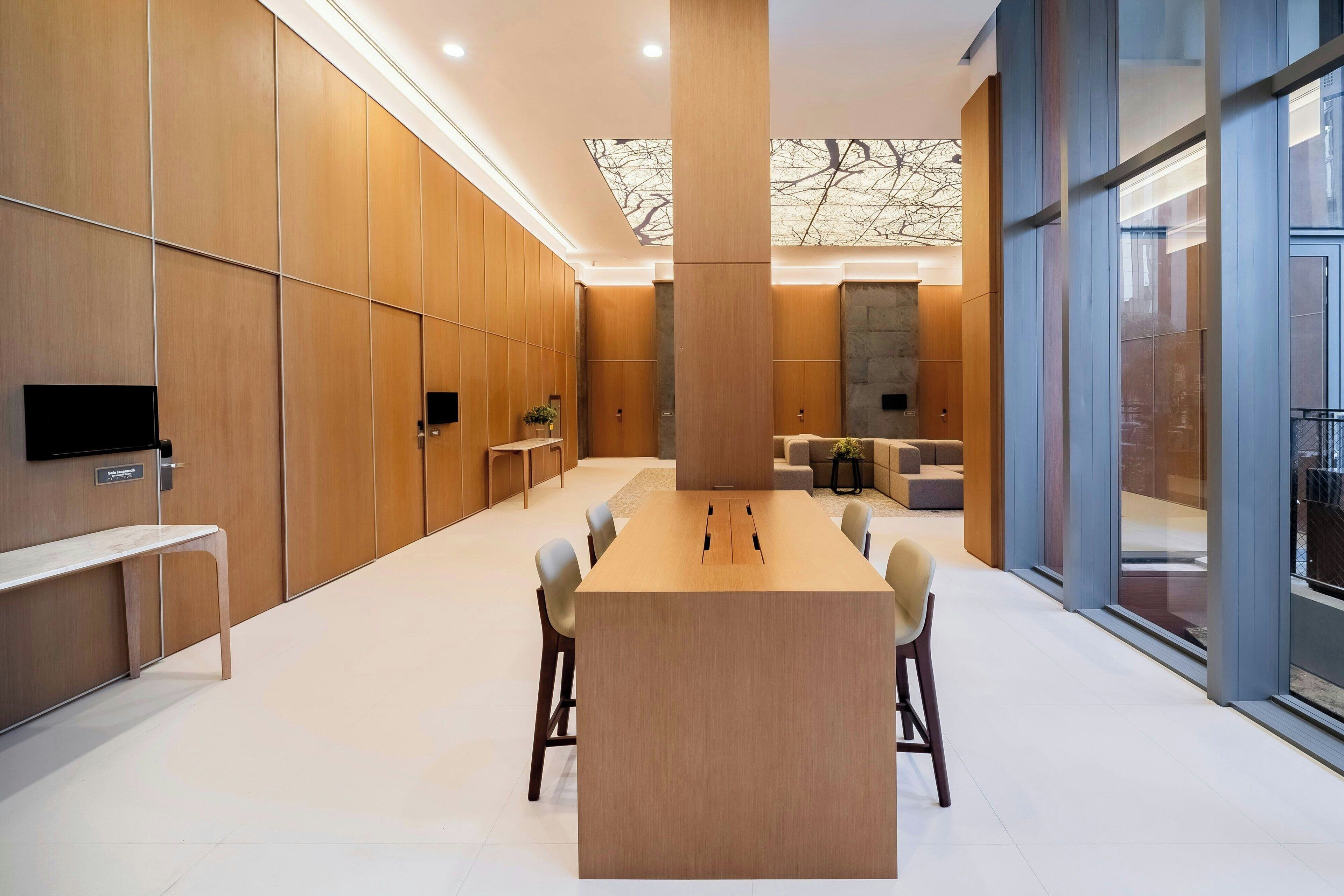 A modern conference room with a long table, chairs, and a TV on the wall.